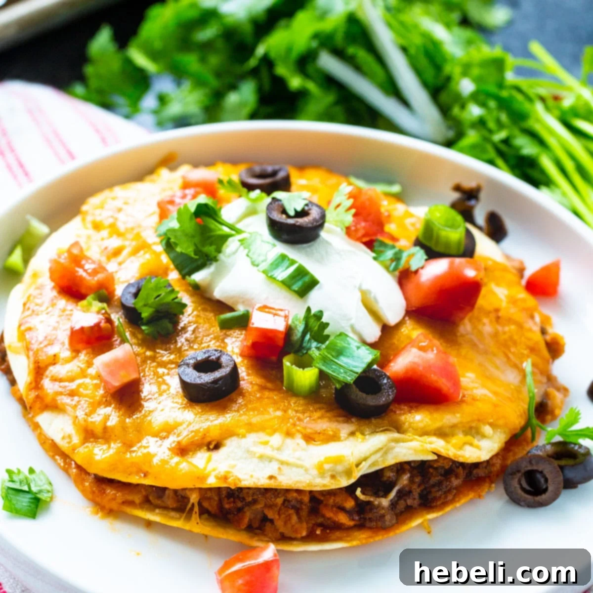 Delicious Taco Bell Mexican Pizza topped with sour cream, diced tomatoes, and sliced olives on a plate, ready to be served.