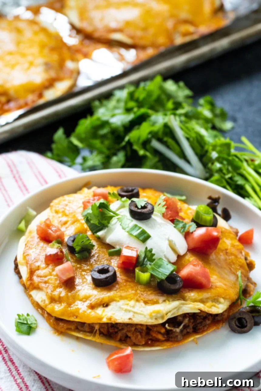 A finished homemade Mexican Pizza with fresh cilantro garnishing, placed on a white plate with a green background.