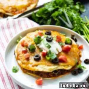 Mexican Pizza on a plate topped with sour cream, olives, and cilantro.