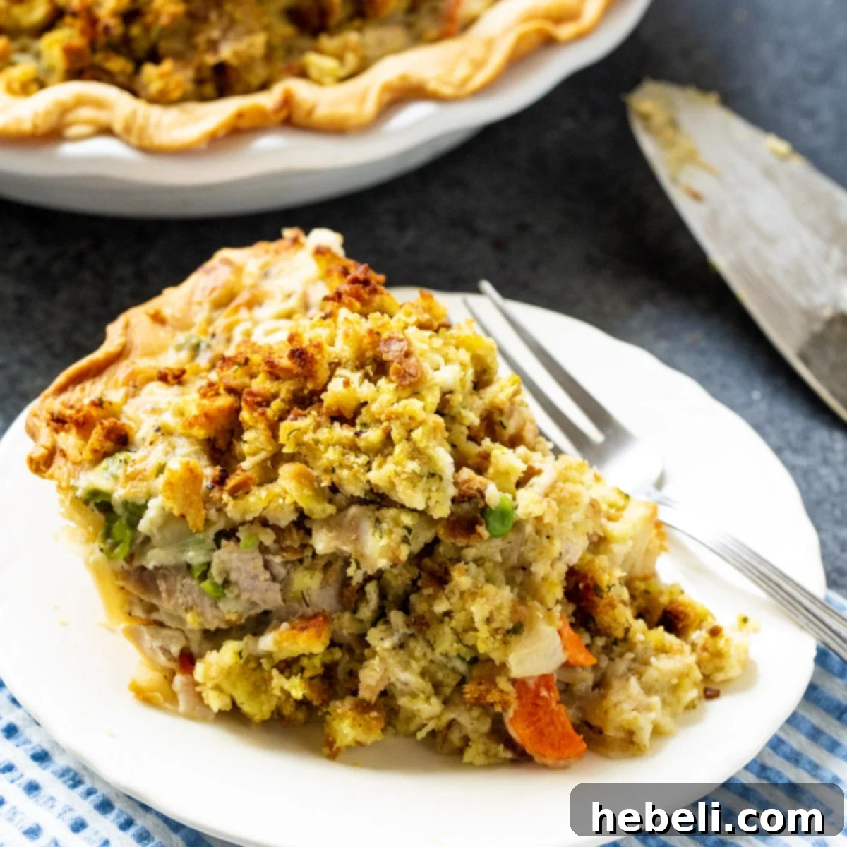 Savory Turkey Pot Pie with Stuffing Crust 2 A perfectly sliced piece of Turkey Pot Pie with stuffing topping, revealing the creamy turkey and vegetable filling, served on a white plate, ready to be enjoyed.
