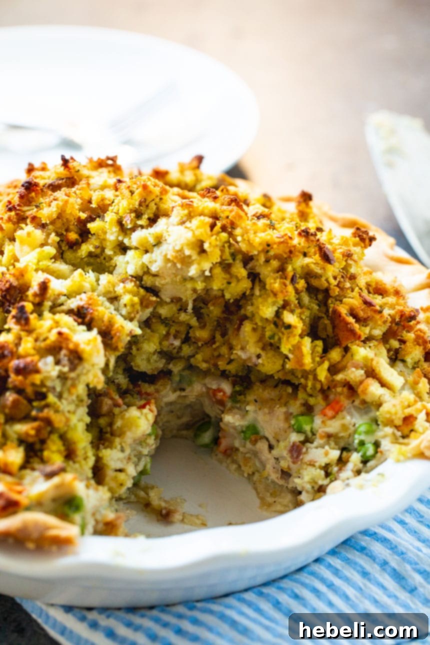 Savory Turkey Pot Pie with Stuffing Crust 4 A Turkey Pot Pie with a slice cut out, showcasing the layers of stuffing, creamy filling, and buttery crust.