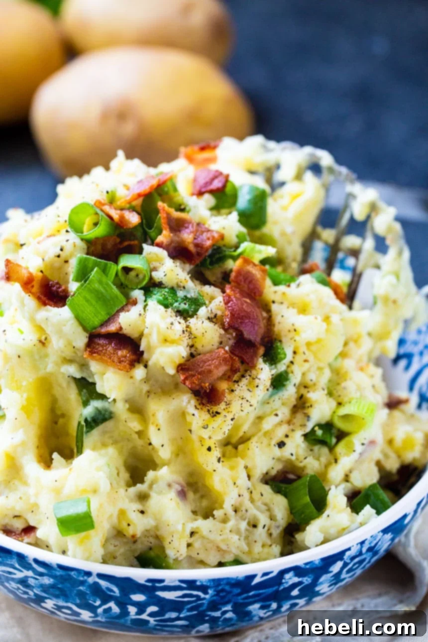 A close-up view of Bacon-Green Onion Mashed Potatoes in a beautiful white serving bowl, ready to be enjoyed. The top is garnished with fresh green onions.
