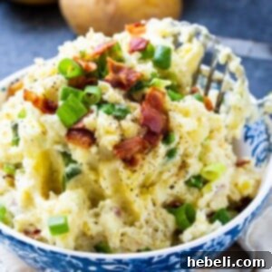 A blue bowl of creamy mashed potatoes with bacon and green onions, ready to serve.