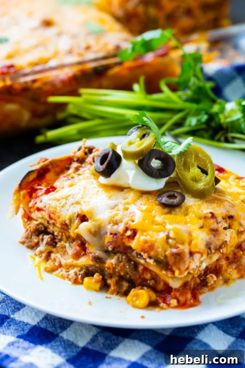 A serving of Mexican Lasagna with the full baking dish in the background, ready for more.