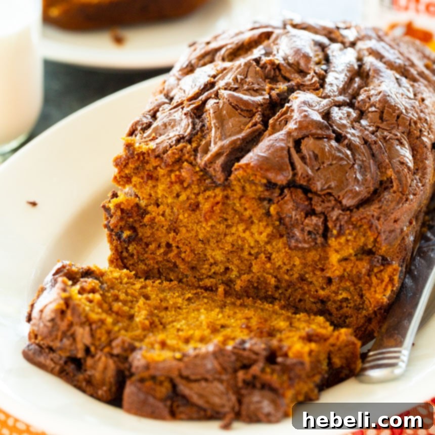 Nutella Swirl Pumpkin Bread 2 Beautifully sliced Nutella Pumpkin Bread on a white serving platter, showcasing rich Nutella swirls.