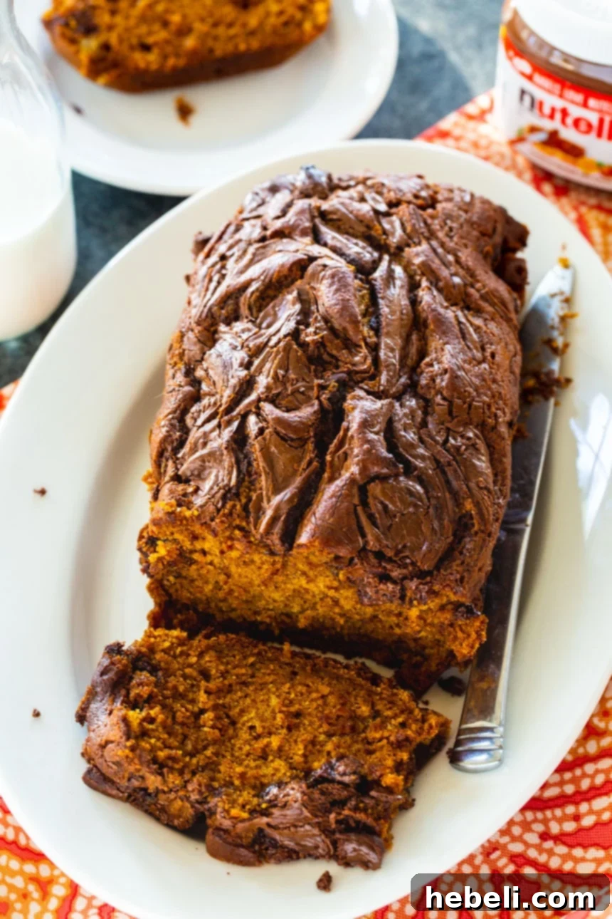 Nutella Swirl Pumpkin Bread 3 Overhead view of a loaf of Pumpkin Nutella Bread with a slice removed, revealing the beautiful swirls.