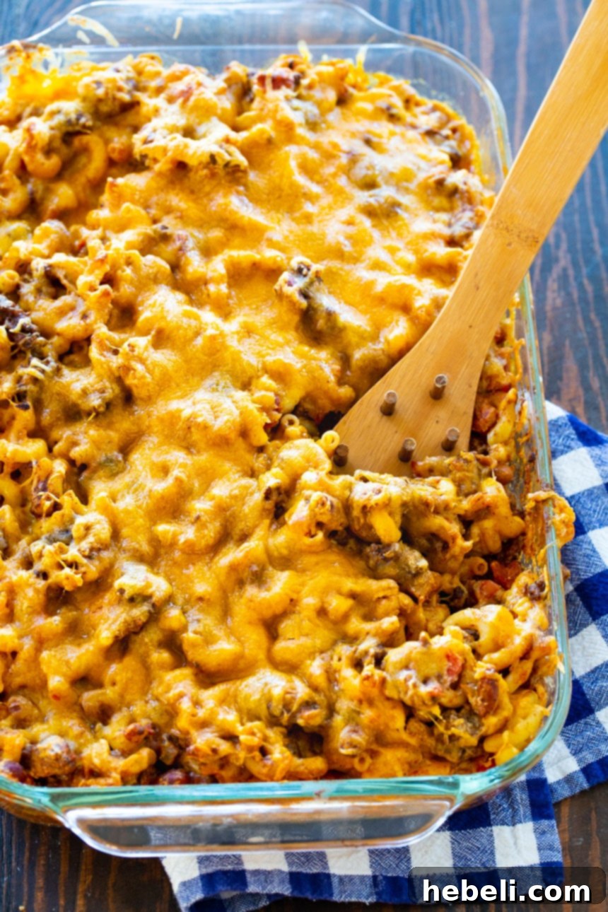 Chili Mac 3 A wooden spoon scooping a generous portion of cheesy Chili Mac from a baking dish.