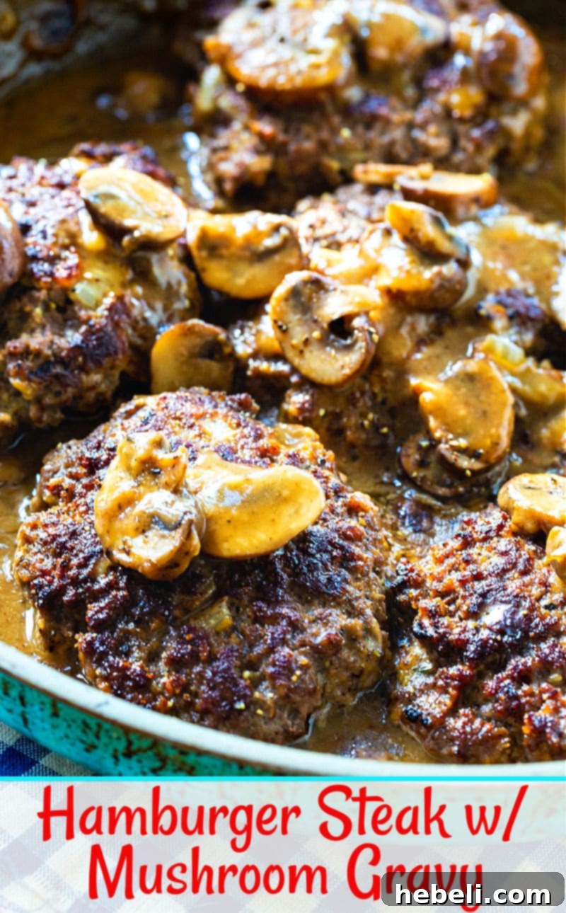 Close-up of a Hamburger Steak covered in rich mushroom gravy on a plate, with a fork ready to dig in, highlighting the tender patty and luscious sauce.