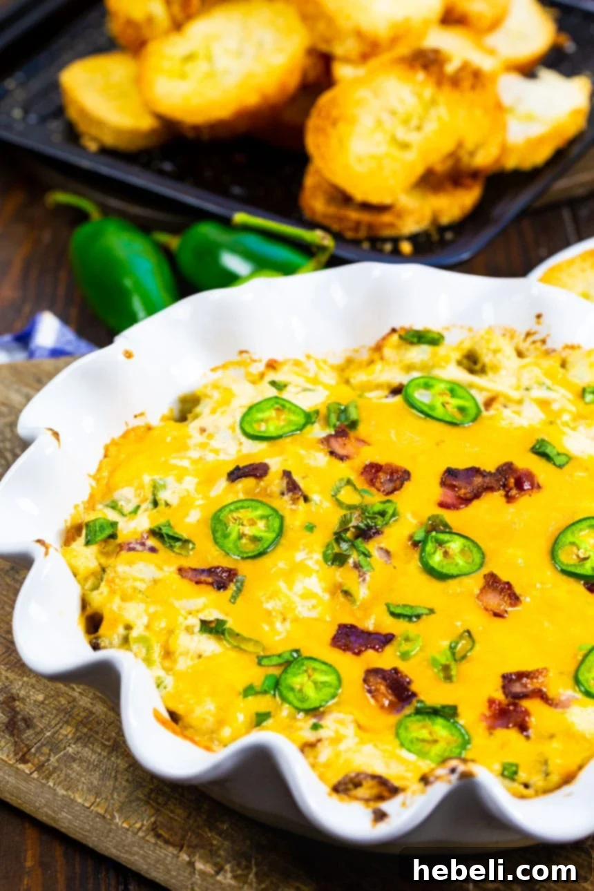 Creamy Jalapeno Crab Dip 4 Crab Dip in a white baking dish with sliced baguette behind it.