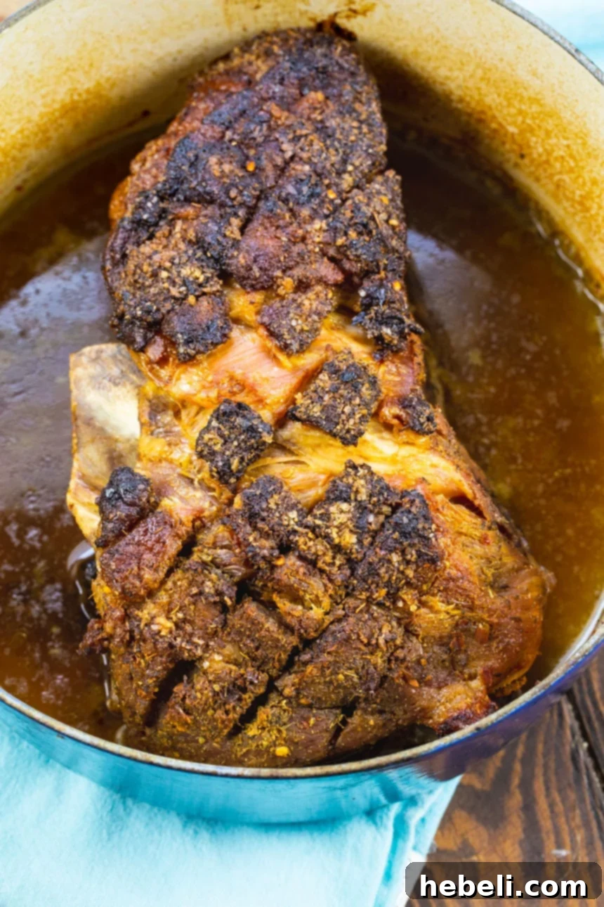 A perfectly cooked, whole pork butt roast resting in a Dutch oven after slow roasting, ready to be prepared for serving.