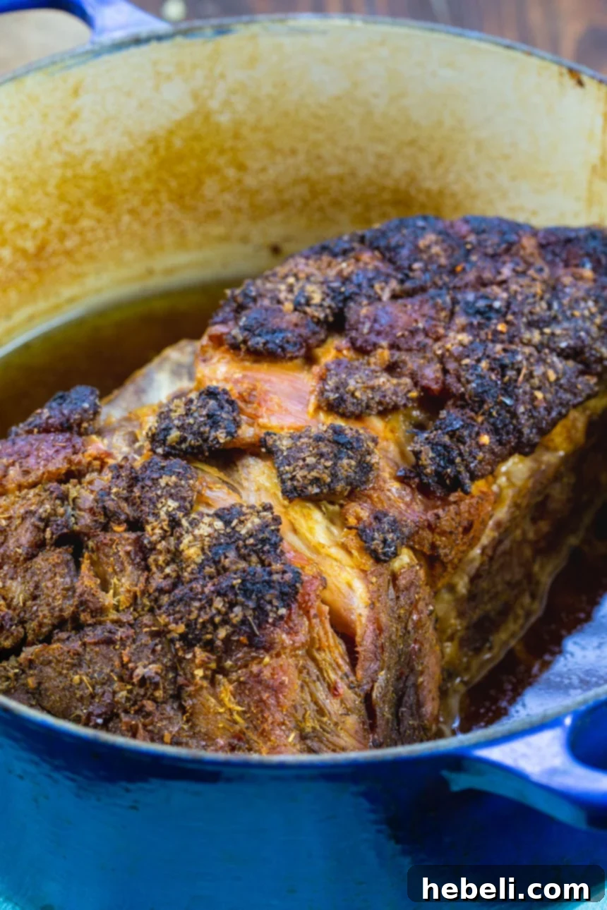 Close-up of tender Cuban Pork Roast in a Dutch oven, succulent and ready to be served, highlighting the crispy exterior.