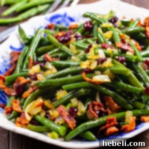 Maple Green Beans on a serving platter, garnished with crispy bacon and dried cranberries.