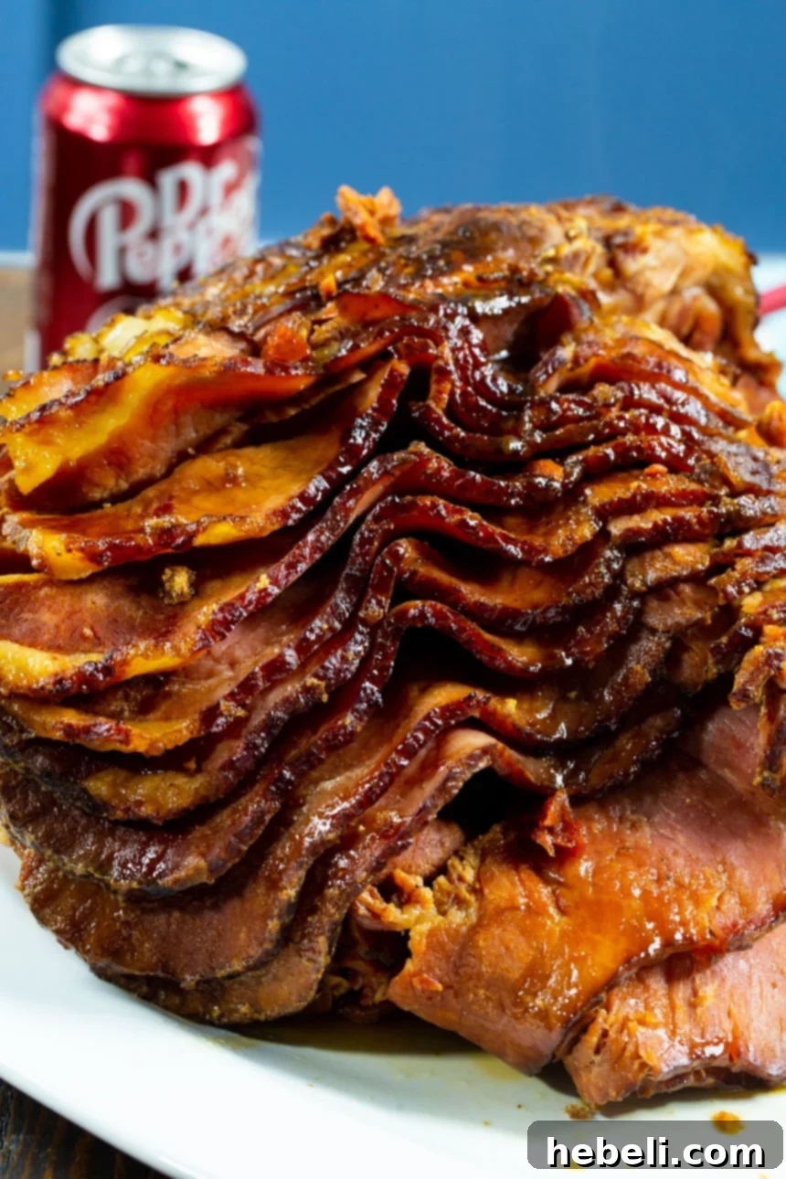 Beautifully sliced Slow Cooker Brown Sugar and Cola Glazed Ham on a serving platter, with a can of Dr. Pepper in the background.