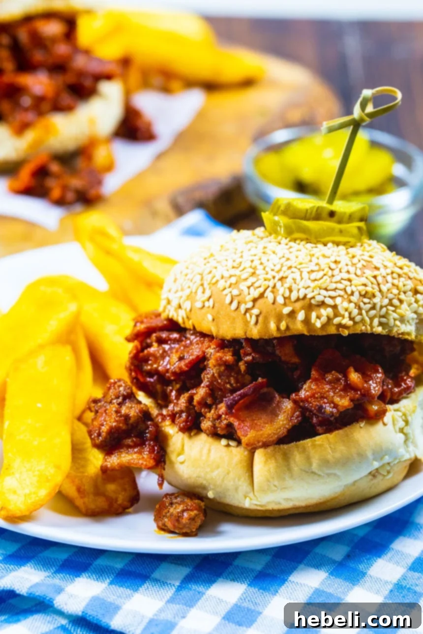 Sweet & Smoky Bacon Sloppy Joes 4 A close-up of a single Brown Sugar Bacon Sloppy Joe on a toasted bun, garnished with some fresh parsley.