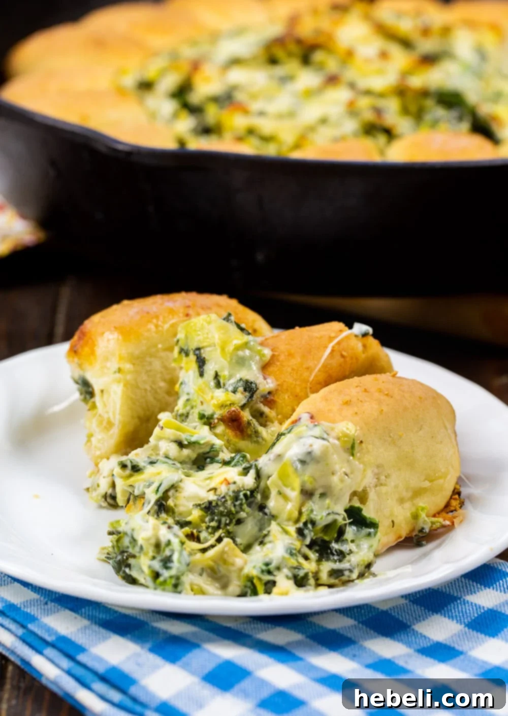 Spinach Artichoke Pull Apart Bread Ring 5 A single roll with a generous scoop of Spinach Artichoke Dip on a plate.