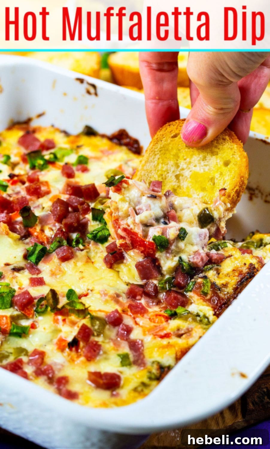 Hot Muffaletta Dip in a serving dish with dippers, perfect for a Mardi Gras celebration or party.