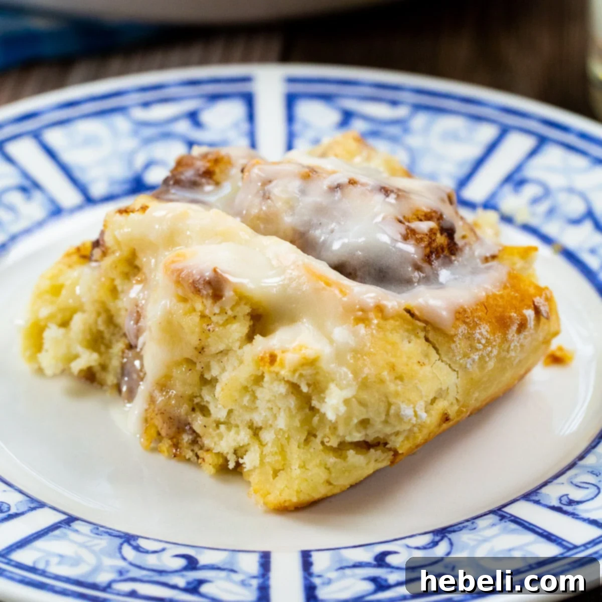 A freshly baked Bisquick cinnamon roll, glazed and inviting, resting on a charming blue and white plate.