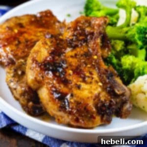 Two Brown Sugar Garlic Pork Chops on a plate with broccoli.