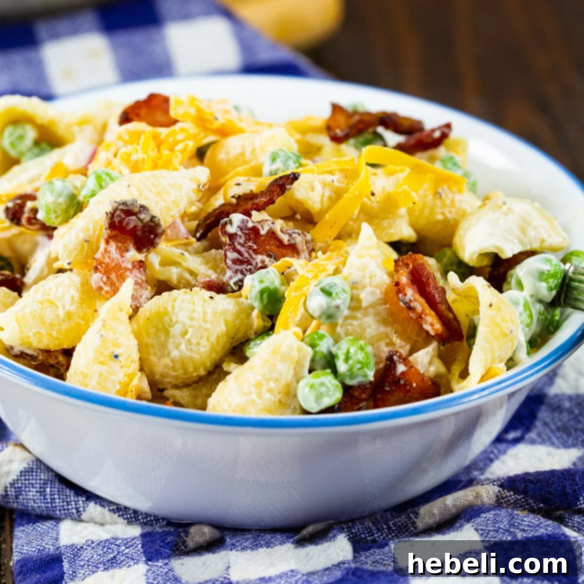 A small bowl overflowing with vibrant Creamy Pasta Salad with Peas and Bacon, garnished with fresh herbs and ready to serve.