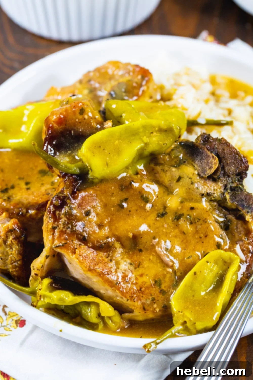 Slow Cooker Mississippi Magic Chops 4 A close-up of tender Mississippi Pork Chops garnished with vibrant green pepperoncini peppers and fresh herbs on a plate.
