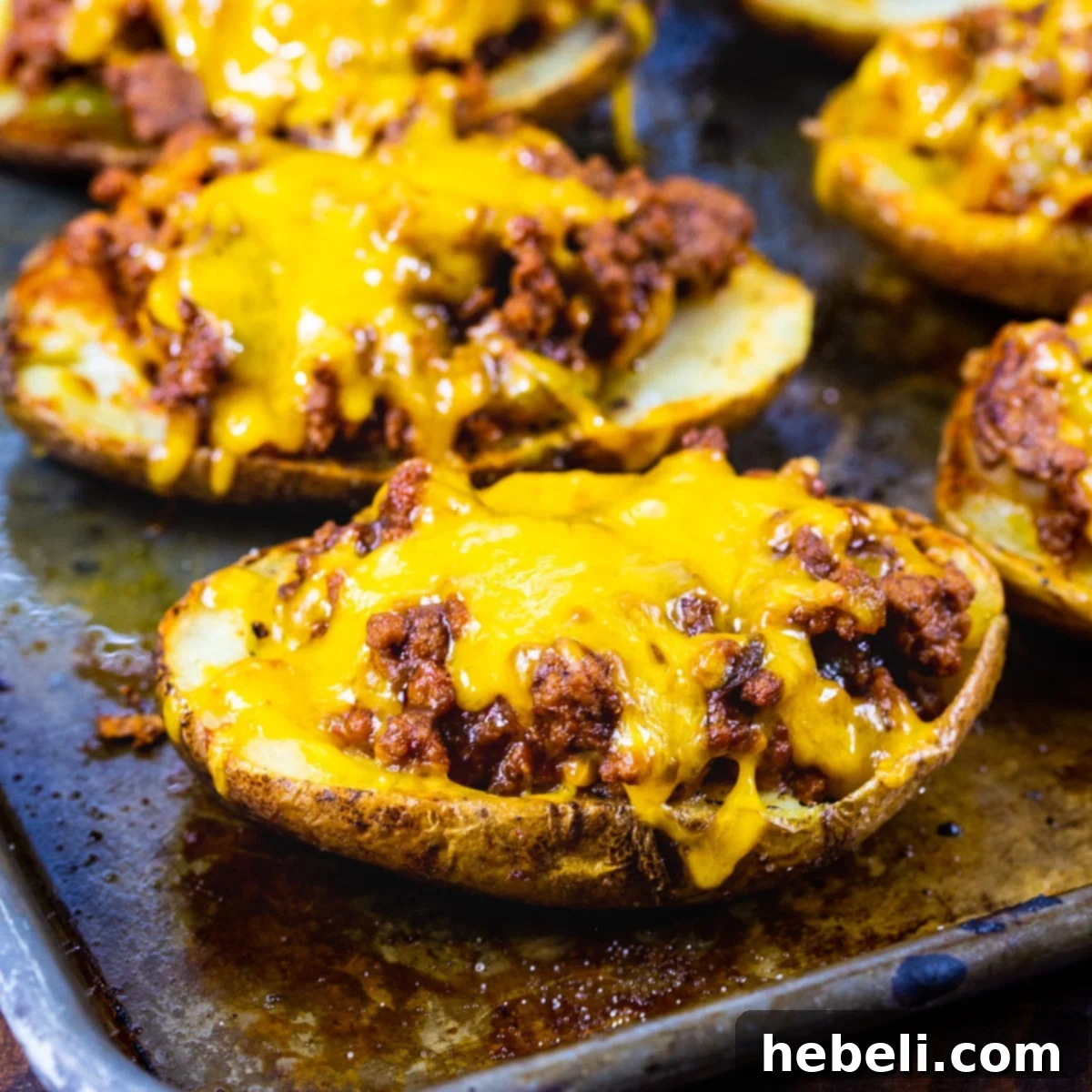 Crispy Sloppy Joe Potato Skins generously filled with meat and cheese, presented on a baking sheet.