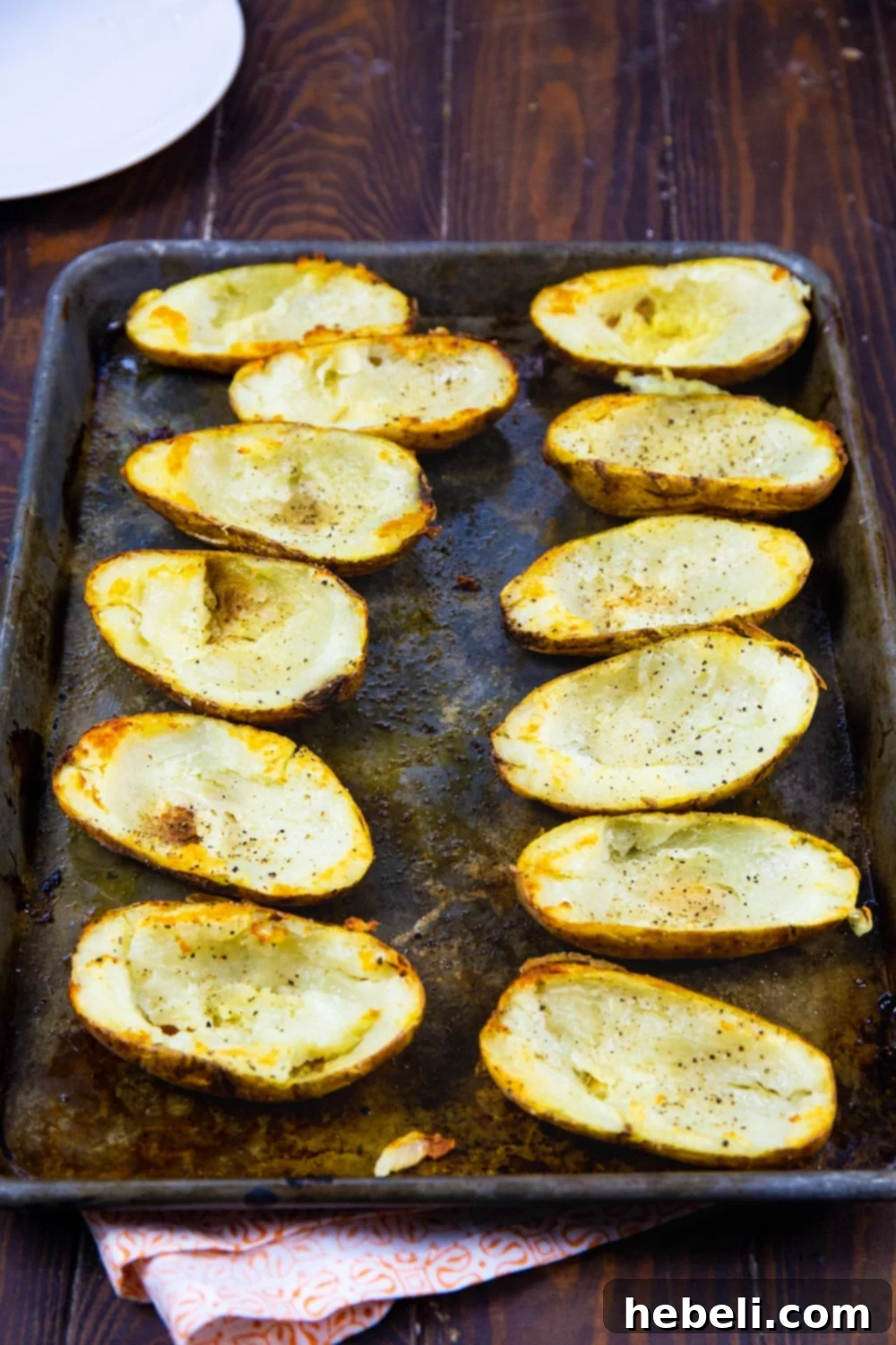 Perfectly hollowed out potato halves, lightly oiled and seasoned, ready for baking on a baking sheet to achieve ultimate crispiness.