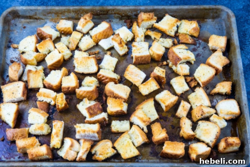 Perfectly toasted bread cubes spread on a baking sheet, golden brown and crispy, ready for the casserole.