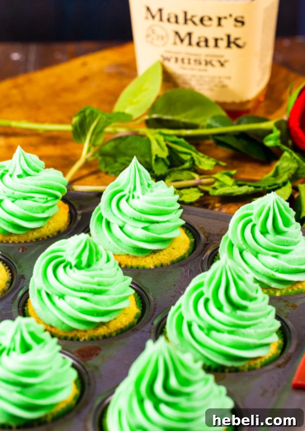 Mint Julep Cupcakes in a baking pan, alongside a bottle of premium bourbon, highlighting key ingredients.