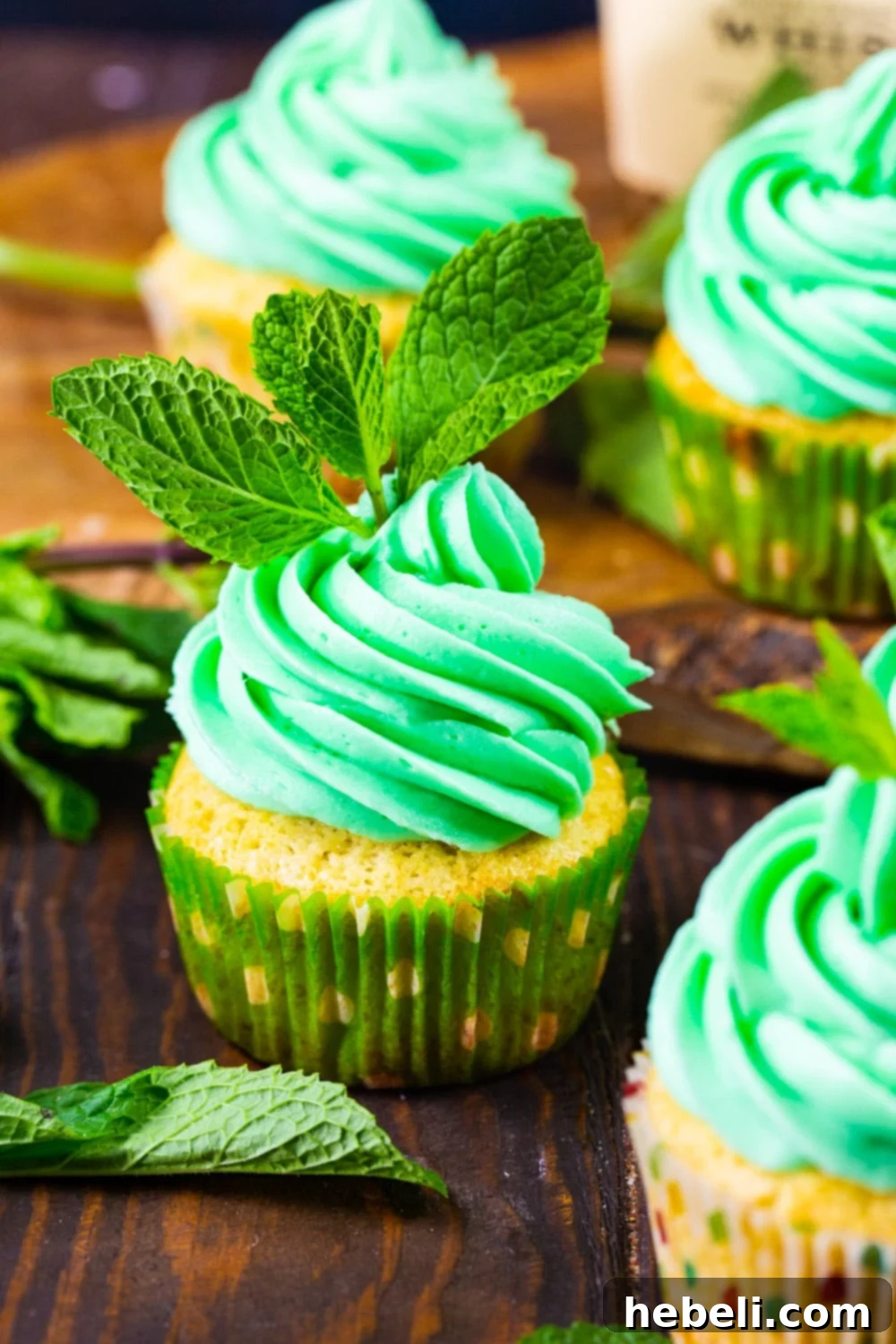 Three Mint Julep Cupcakes adorned with green icing and fresh mint sprigs, ready for indulgence.