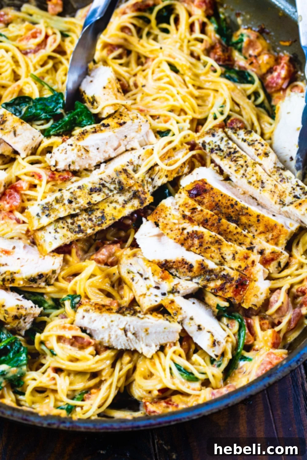 Creamy Tuscan Chicken Pasta 3 Tuscan-Style Pasta with chicken and spinach in a large skillet, ready to be tossed.