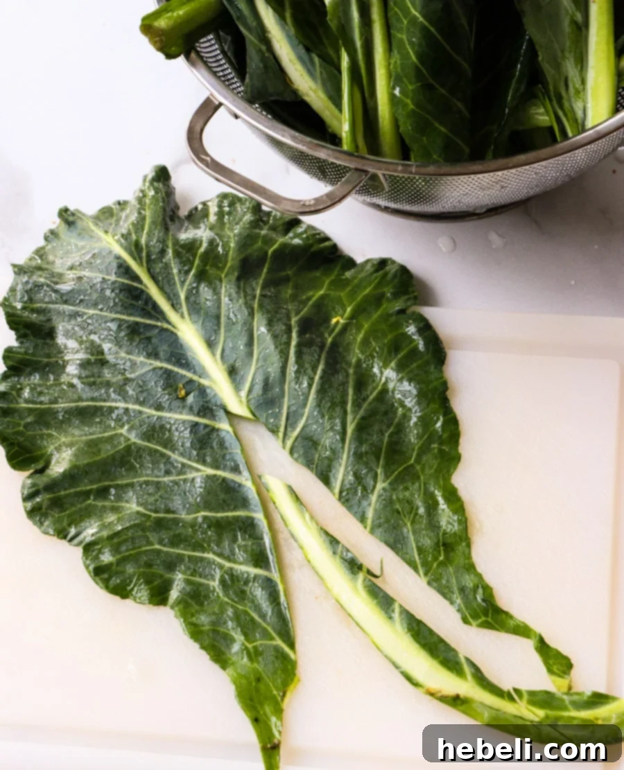 Smoky Chipotle Braised Greens 3 Detailed image showing the process of cutting out the thick central rib from a collard green leaf, preparing it for slicing.