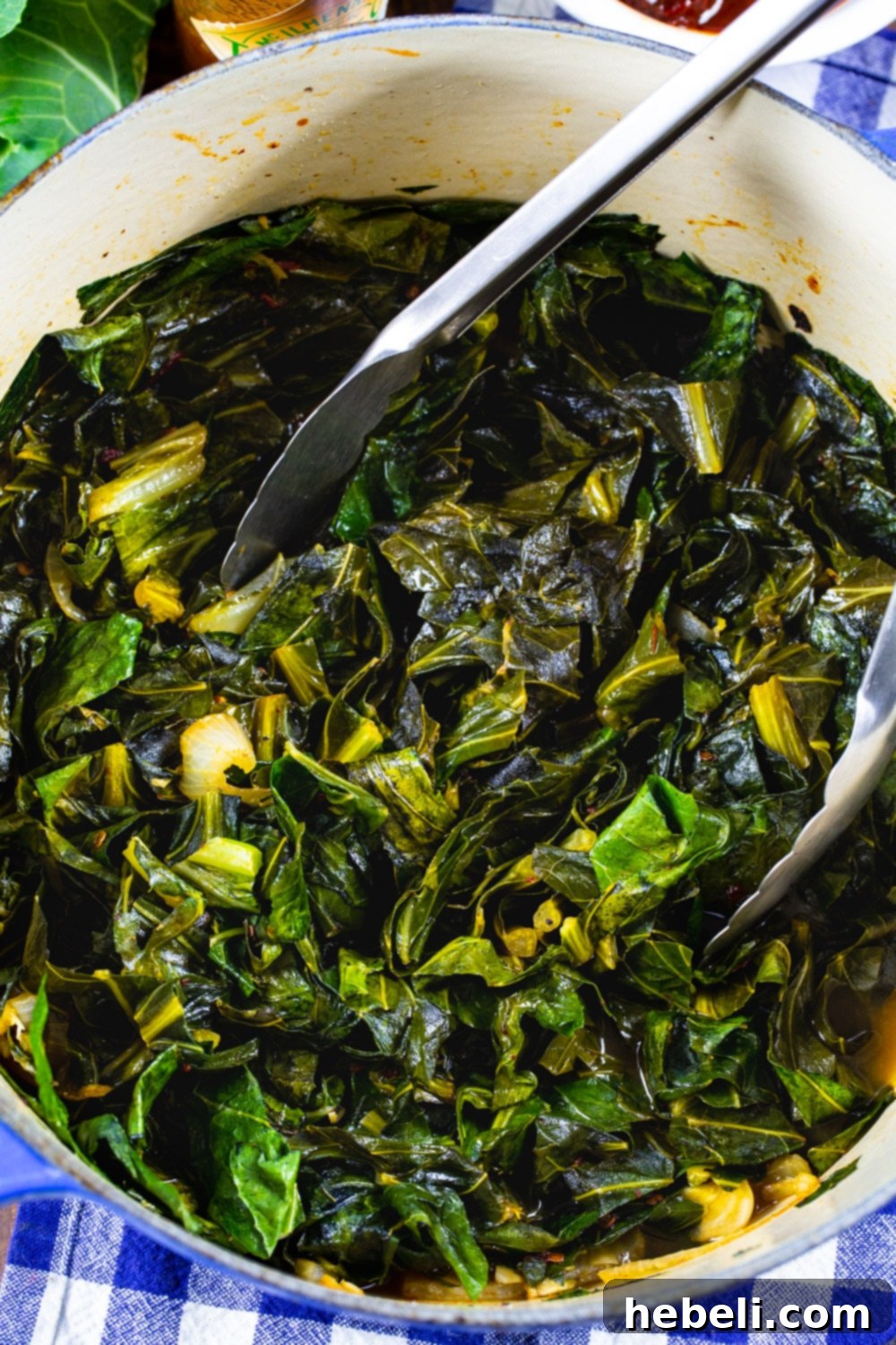 Smoky Chipotle Braised Greens 5 Freshly chopped collard greens, onions, and chipotle peppers are simmering in a Dutch oven, releasing aromatic steam.