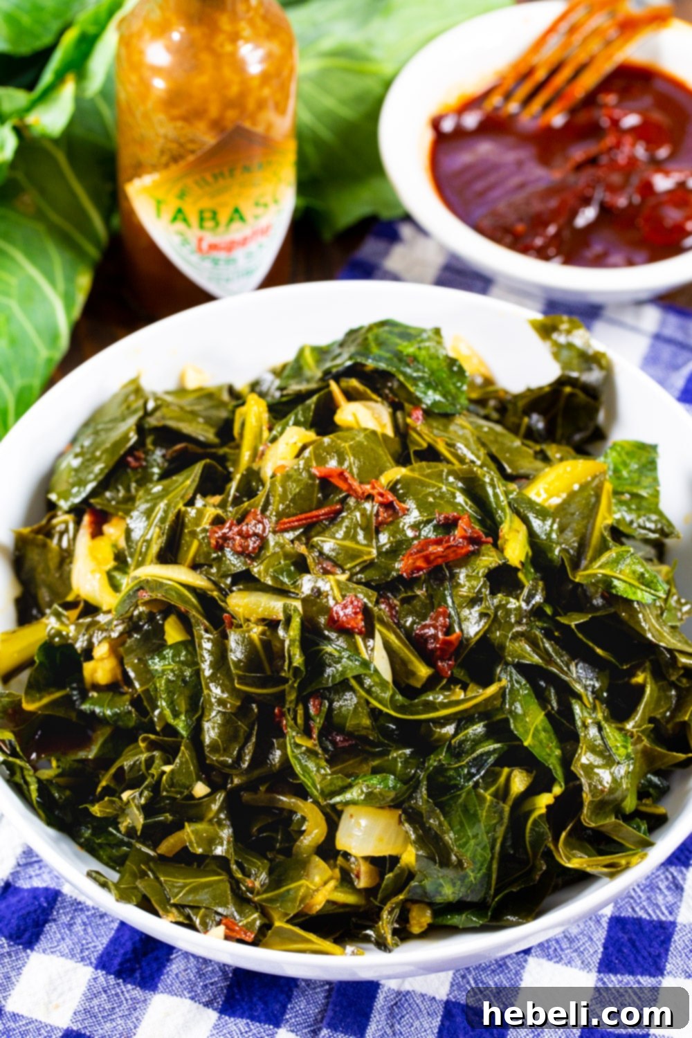 Smoky Chipotle Braised Greens 6 A vibrant bowl of Chipotle Collard Greens, garnished with a dash of hot sauce, highlighting their rich, smoky, and spicy flavor profile.