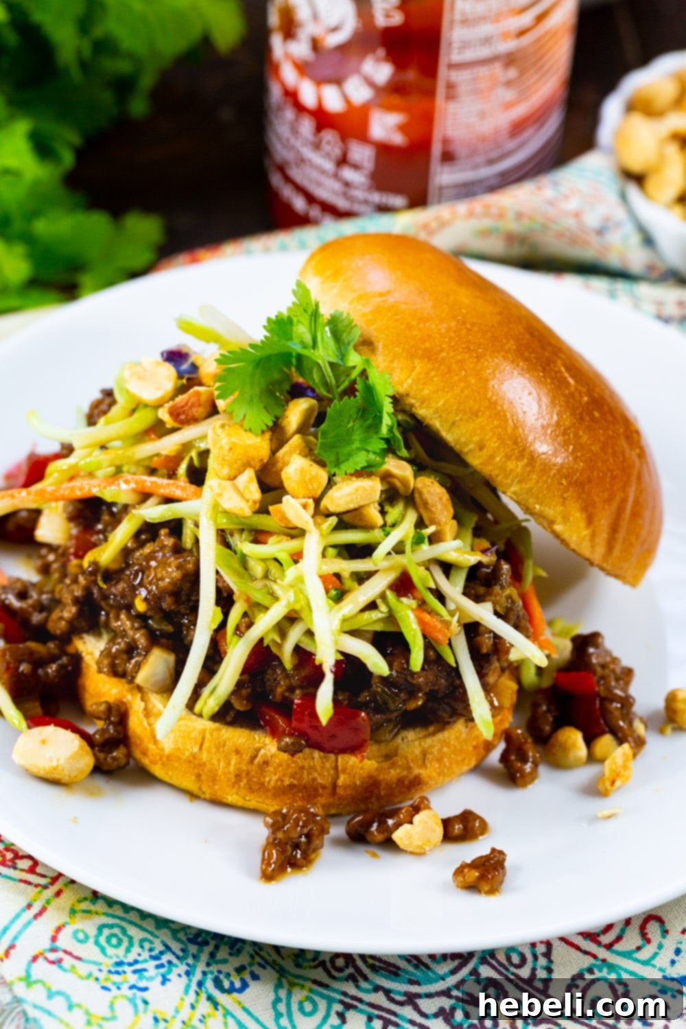 A close-up view of a single Kung Pao Sloppy Joe on a plate, highlighting its rich filling and vibrant toppings.