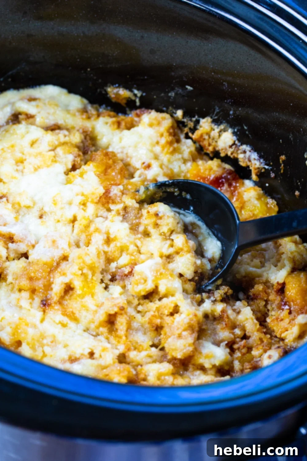 Spoon scooping Crock Pot Peaches and Cream Cake out of slow cooker.