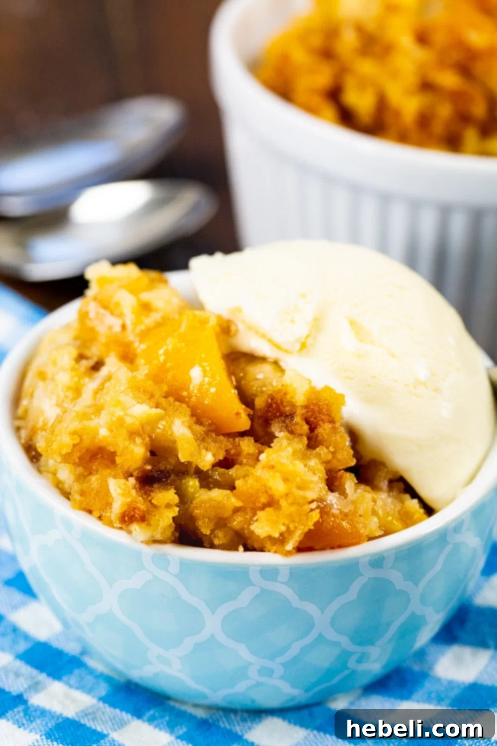 Peaches and Cream Cake topped with ice cream in a bowl.