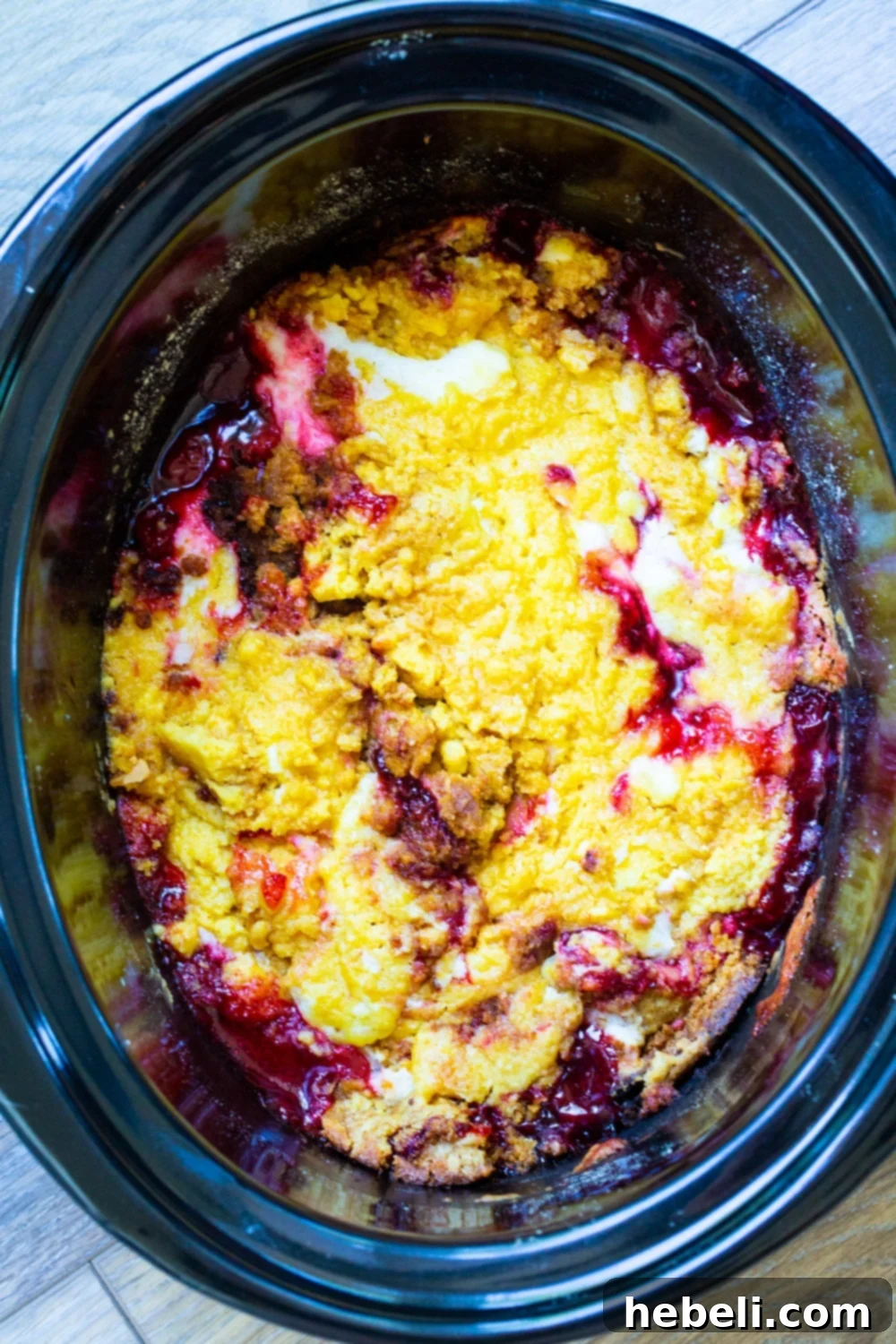 Cherries and Cream Cake in a black slow cooker, steaming hot.