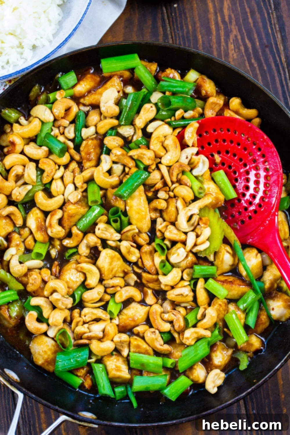 Classic Cashew Chicken 3 Close-up of Cashew Chicken simmering in a large nonstick skillet, showing the glossy sauce coating the chicken, celery, and cashews.