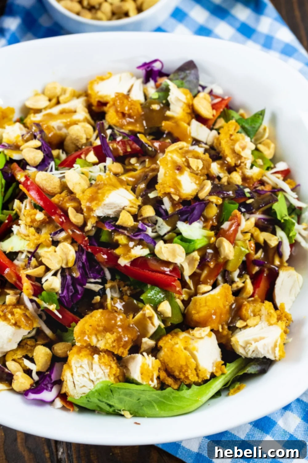 Chopped Salad with chicken tenders and peanut dressing in a large white bowl, ready to be served.