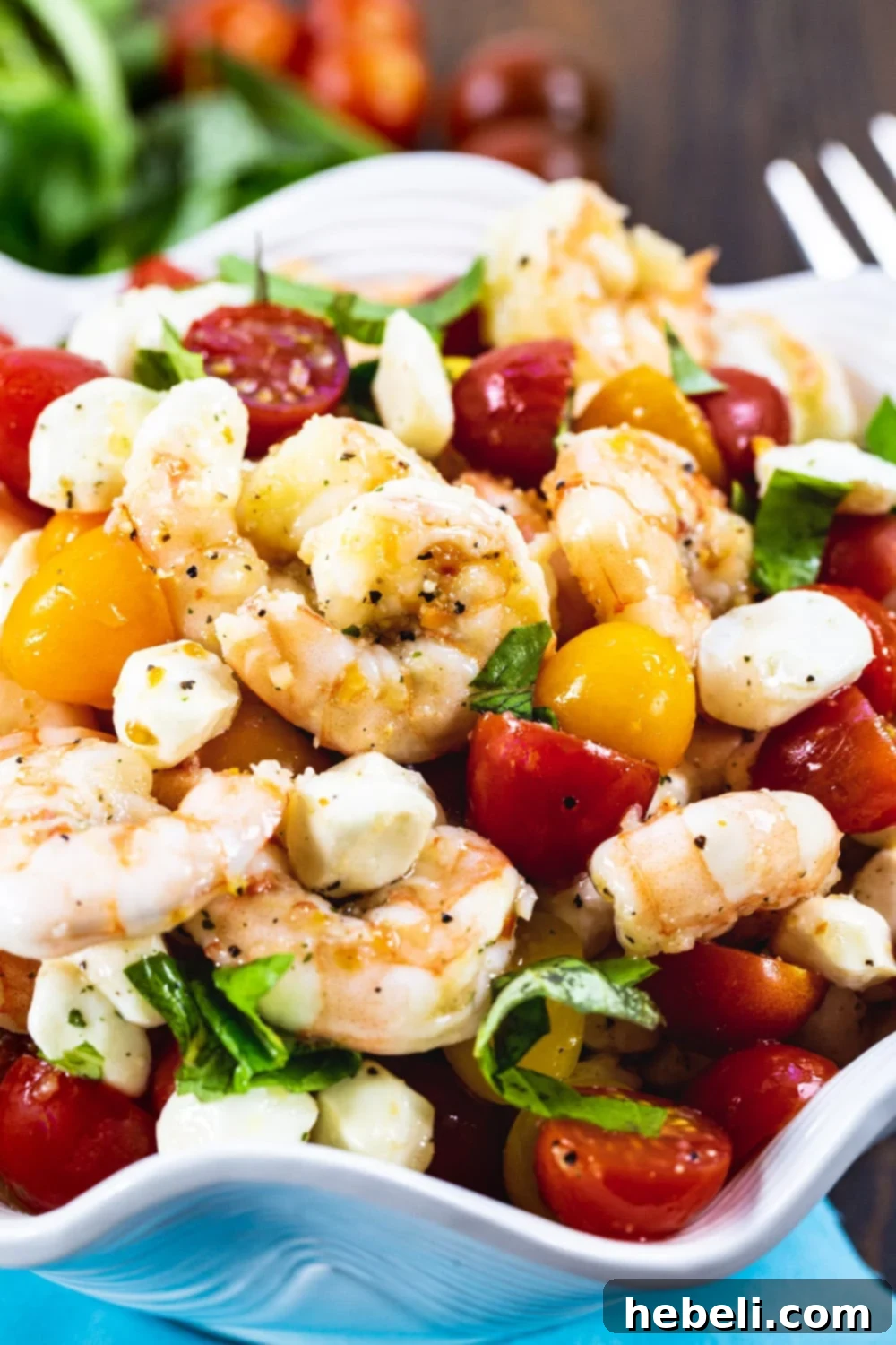 Shrimp Salad with cherry tomatoes and mozzarella balls in white serving bowl, close up.