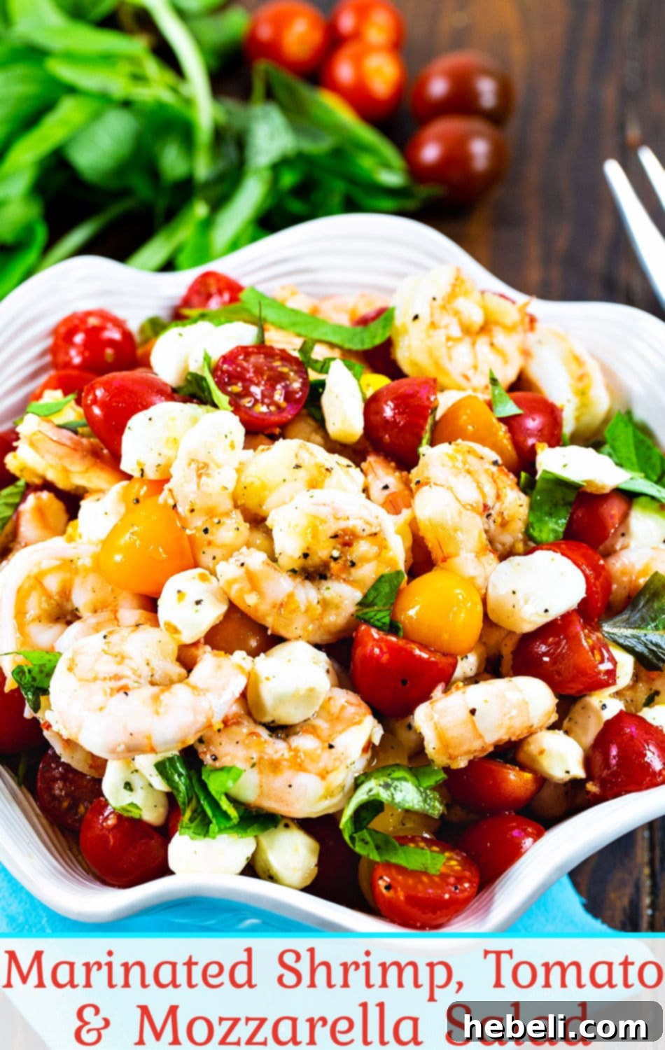 Marinated Shrimp, Tomato, and Mozzarella Salad in a clear bowl with serving spoon, garnished with basil.
