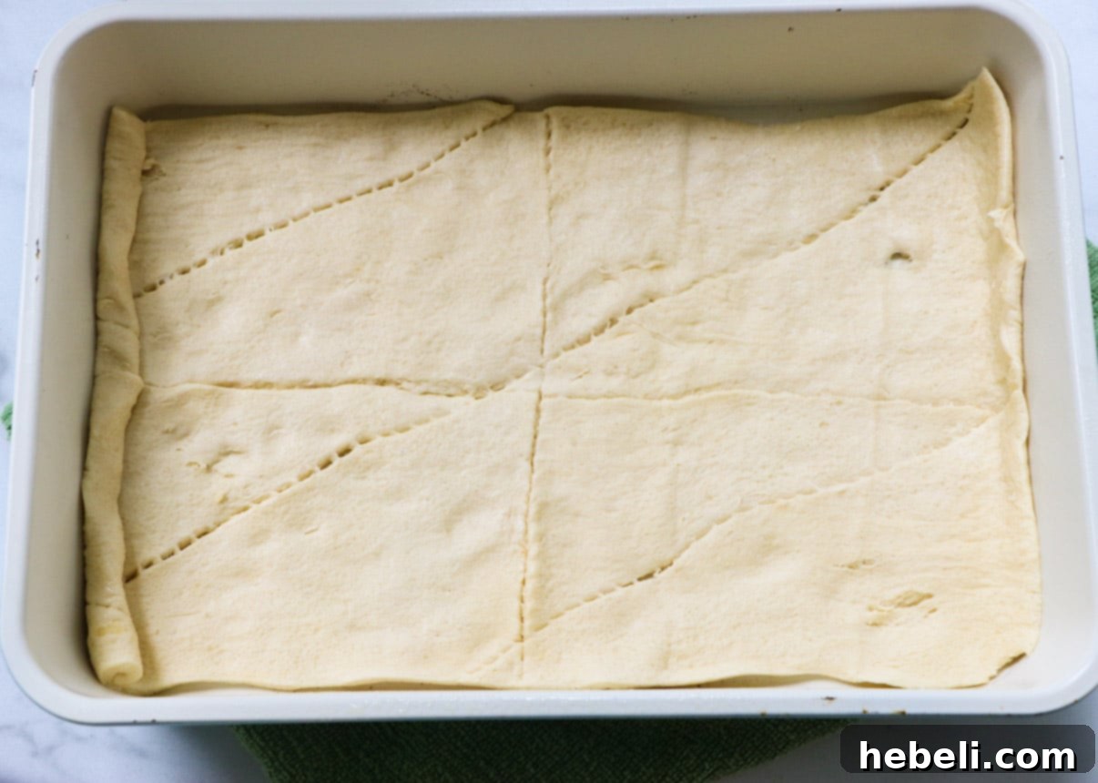 Luscious Peach Cream Crescent Bars 3 Crescent roll dough spread in the bottom of a 9x13-inch baking dish.