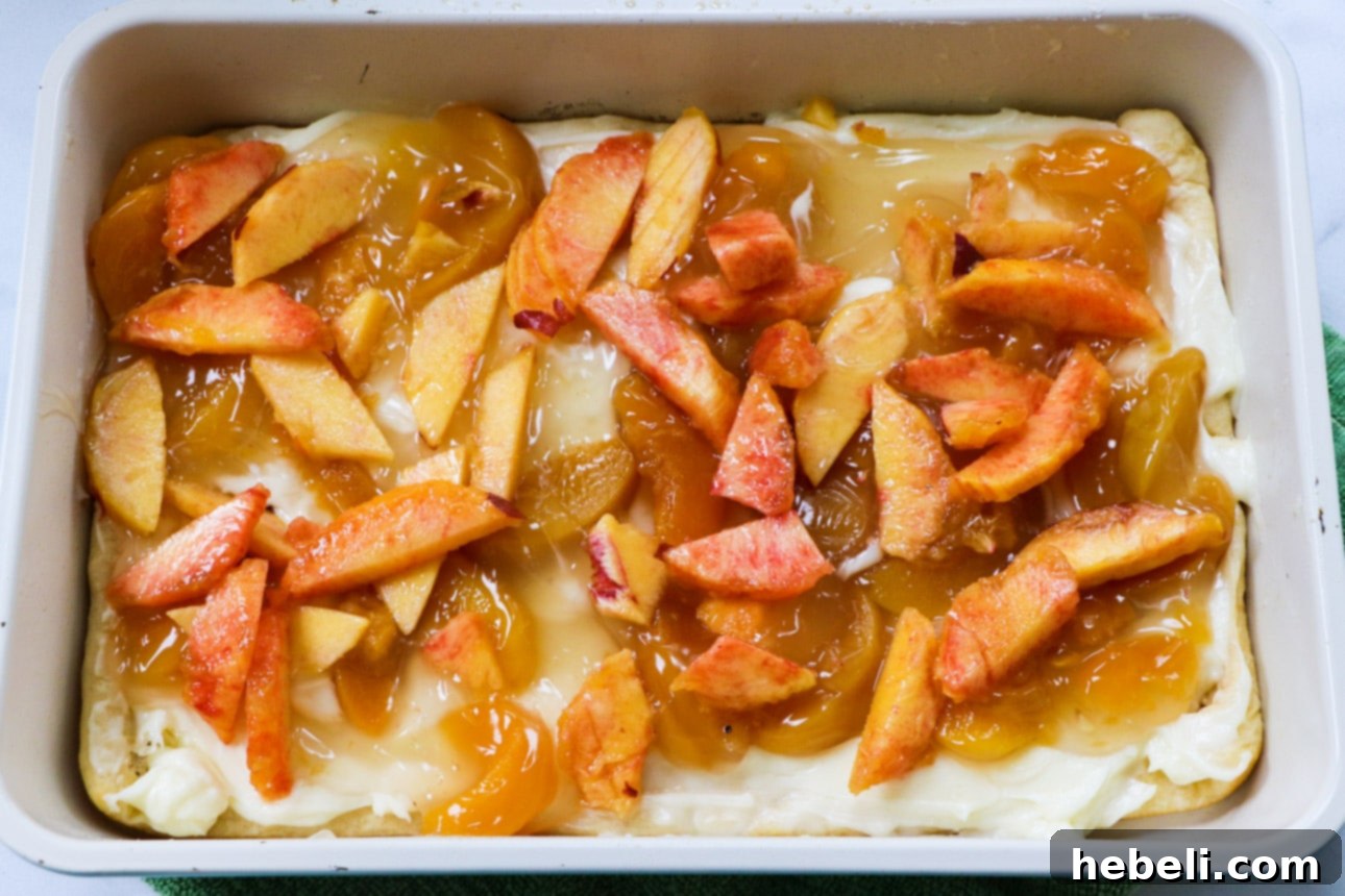 Luscious Peach Cream Crescent Bars 4 Fresh peach slices arranged on top of the cream cheese layer in a baking dish.