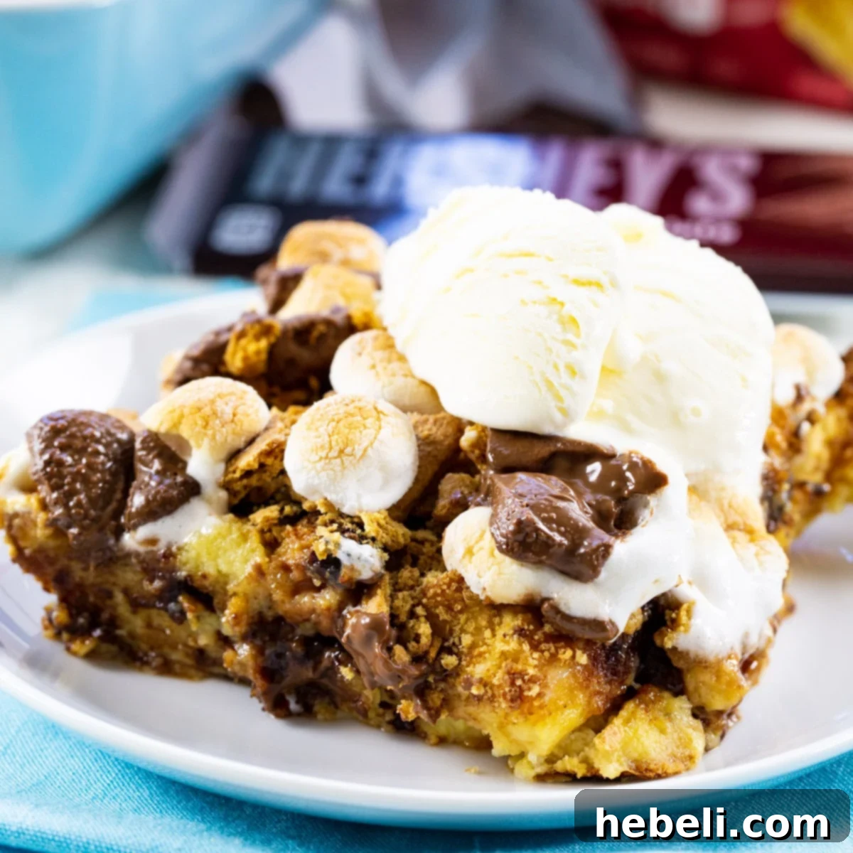 A delectable slice of S'mores Bread Pudding, perfectly golden-brown and topped with a melting scoop of vanilla ice cream, promising a harmonious blend of warm and cool textures.
