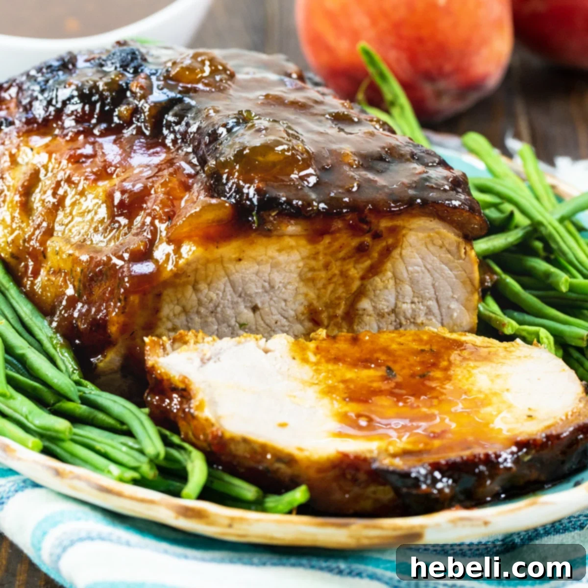 Sweet Peach Pork Perfection 2 A beautifully roasted Peach Glazed Pork Roast surrounded by vibrant green beans on an elegant serving platter, ready to be enjoyed.