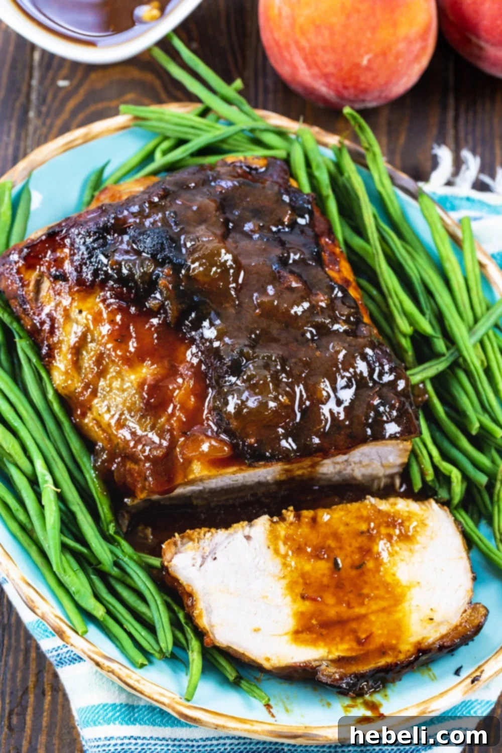 Sweet Peach Pork Perfection 3 Close-up of a succulent Pork Roast artfully arranged on a serving platter with fresh green beans, highlighting its golden-brown glaze.