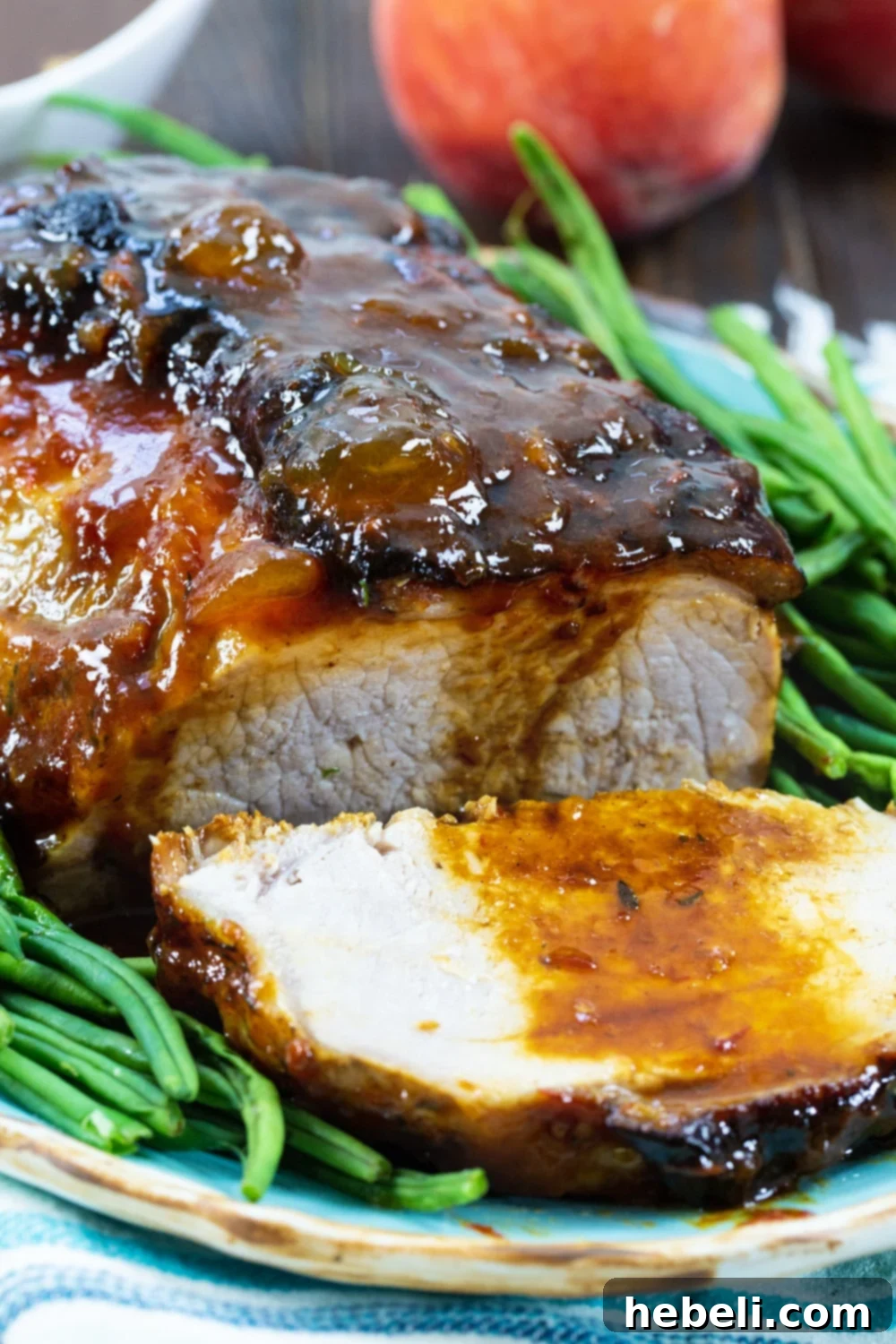 Sweet Peach Pork Perfection 4 A slice of Peach Glazed Pork Roast, showing its juicy interior and golden glaze, presented with vibrant green beans.