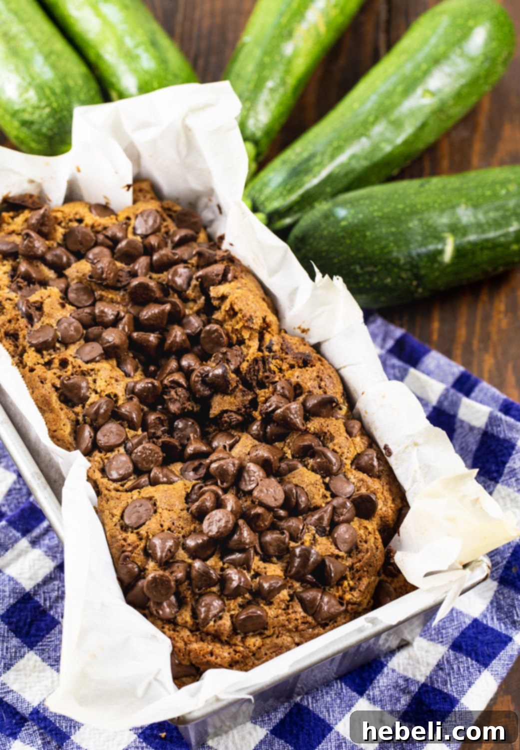 Decadent Chocolate Zucchini Loaf 3 Freshly baked Chocolate Zucchini Bread in a loaf pan, surrounded by whole garden zucchini.