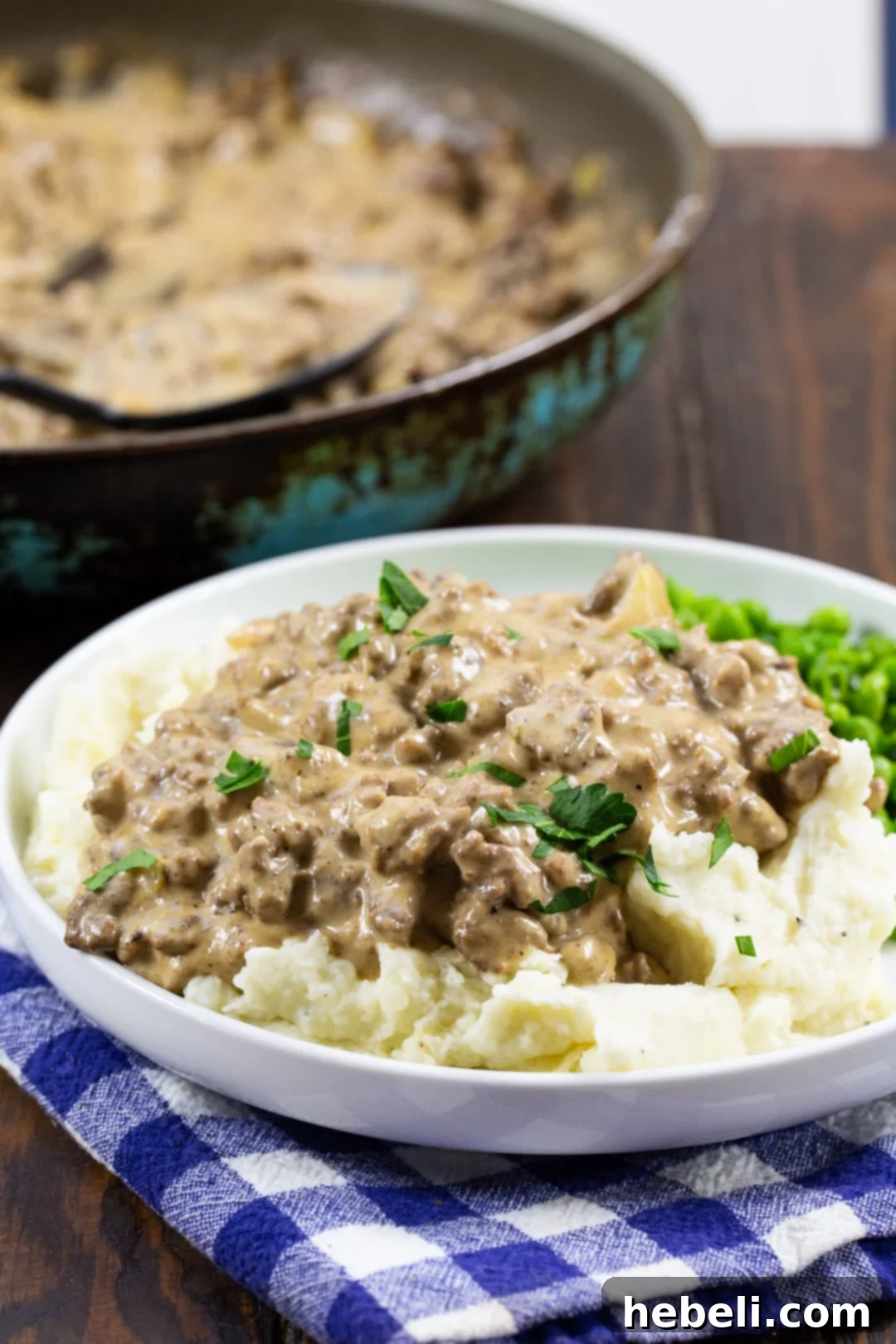 Easy Hamburger Gravy dished up on a plate with skillet in background, ready to be served.