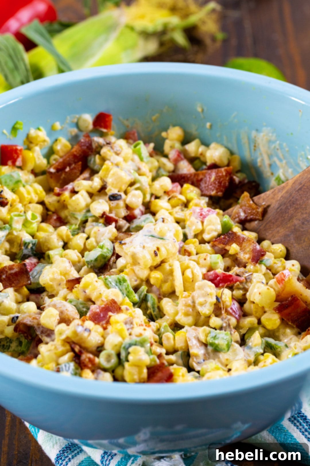 Zesty Chipotle Corn Medley 3 Corn Salad in blue mixing bowl with wooden spoon.